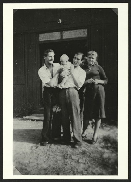 “De jongste bewoner van het Ostlager, Berlijn 1943". Zwei holländische Männer halten ein Baby, die russische Mutter steht daneben vor Barackeneingang, Dokumentationszentrum NS-Zwangsarbeit/Sammlung Berliner Geschichtswerkstatt, dzsw1961